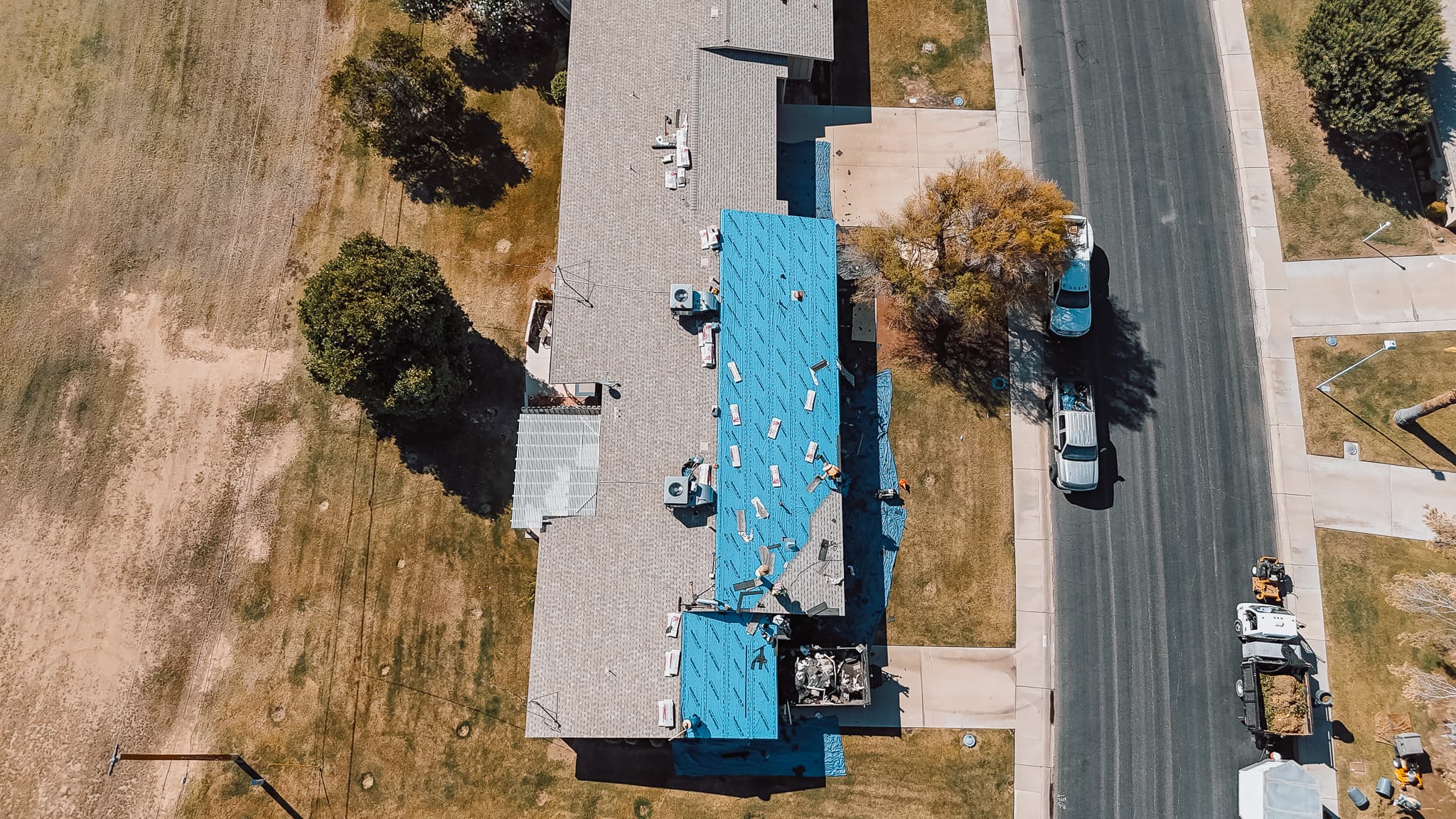 Aerial drone view of a HailCo Roofing replacement in progress, with new underlayment and shingle going down across a Phoenix Valley property