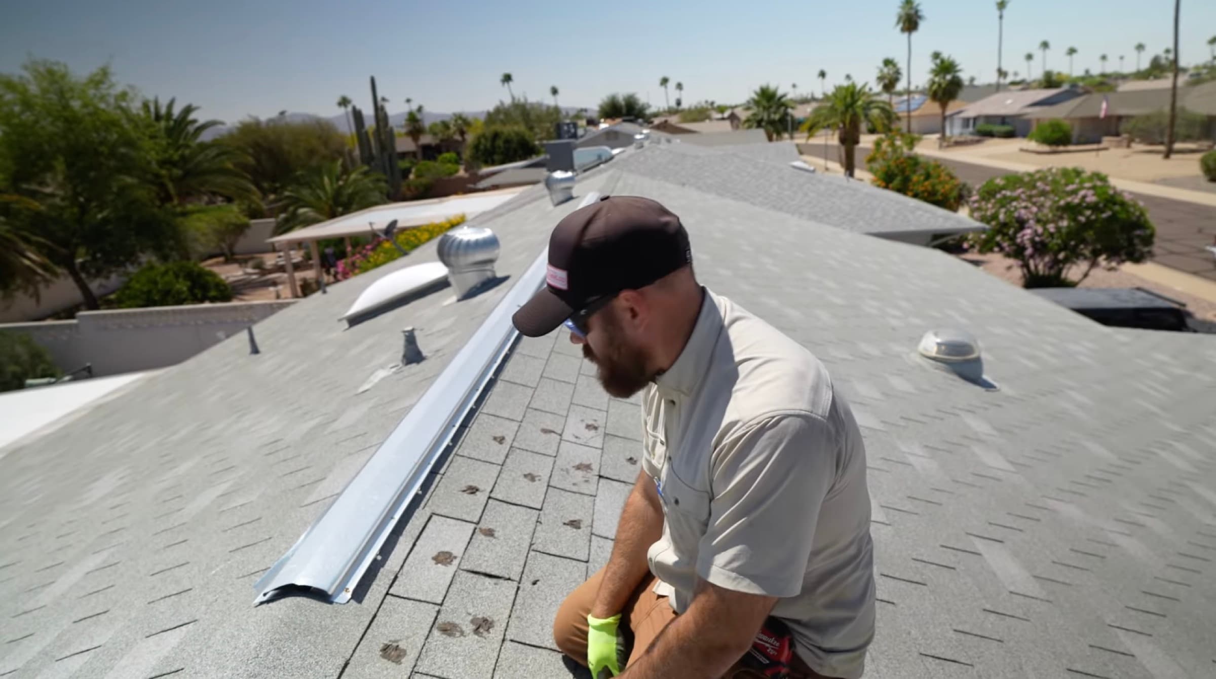 HailCo Roofing owner inspecting wind-lifted ridge cap after an Arizona monsoon storm