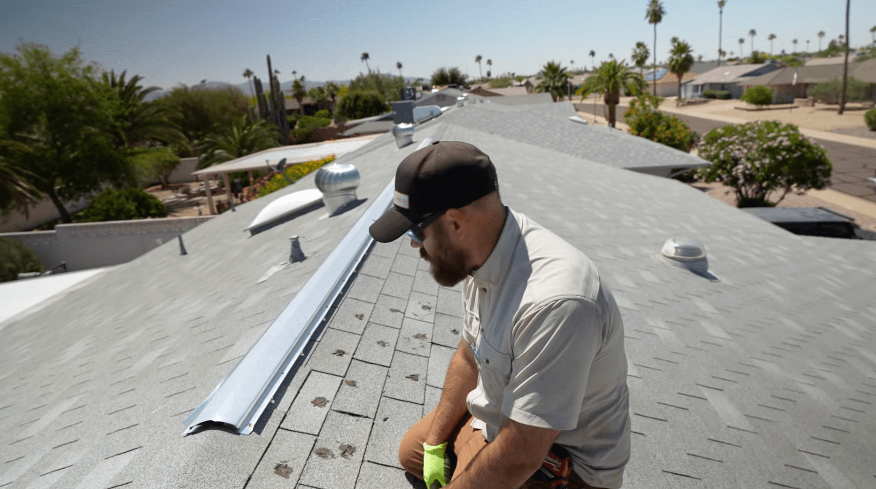 HailCo Roofing owner inspecting wind-lifted ridge cap after an Arizona monsoon storm